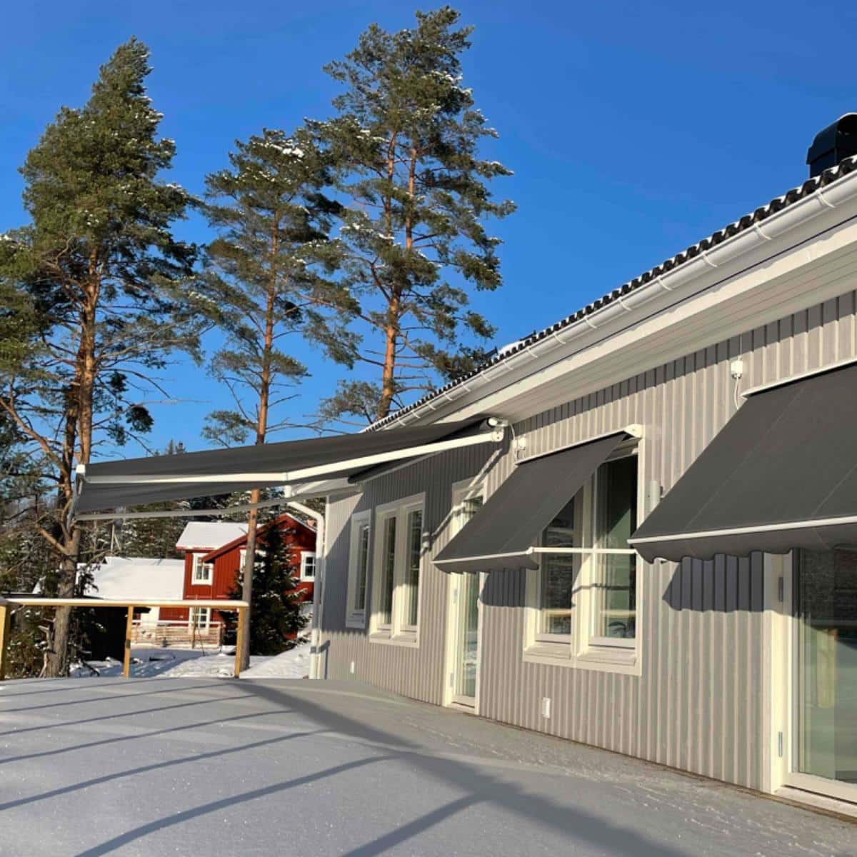 Grått hus med flera grå markiser som skyddar mot solen