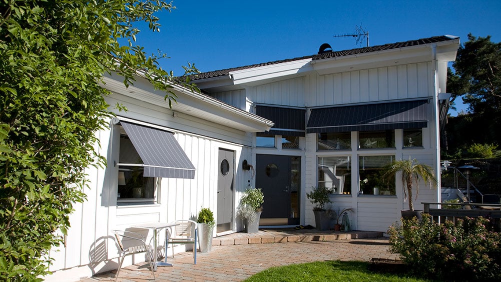 Vit villa med nedfällda fönstermarkiser.