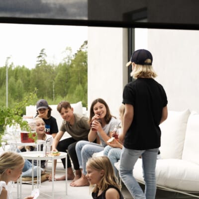 Svart rullgardin som solskydd vid altandörr.