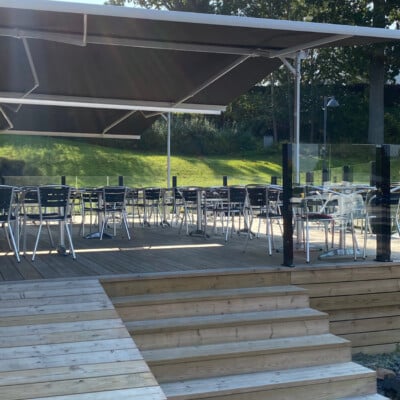 Svarta markiser över uteservering med bord och stolar