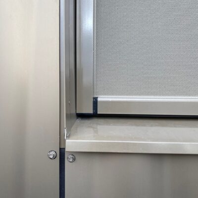 Detalj av metallinfattad screenmarkis i nedfällt läge.