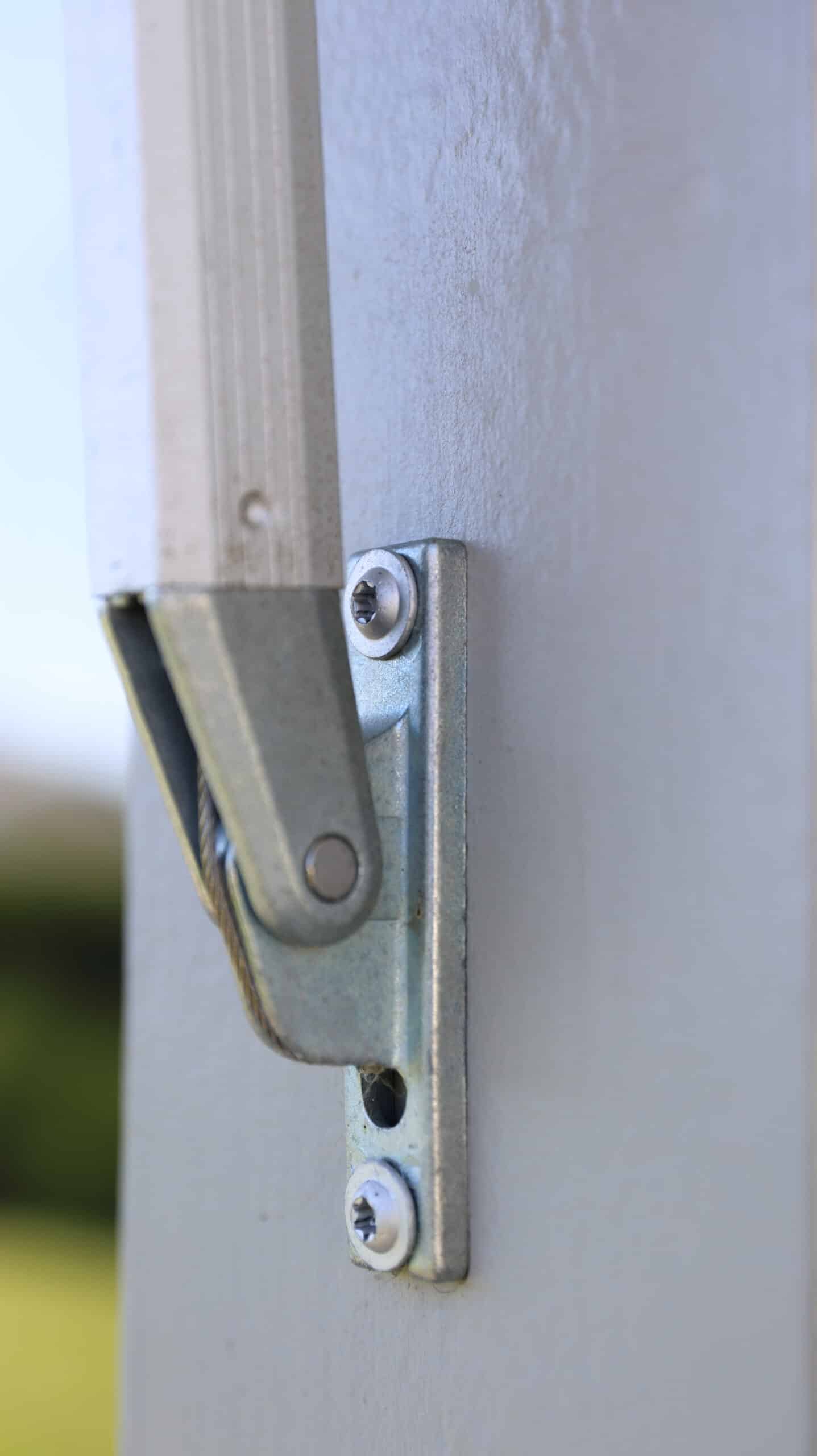 Närbild på metallfäste för markis monterat på trävägg