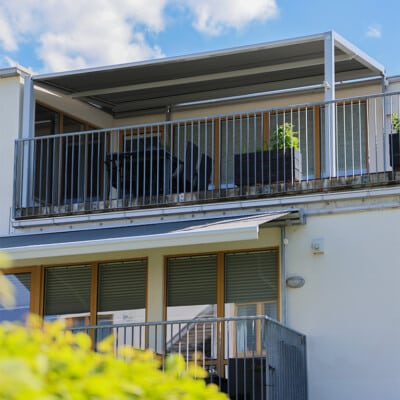 Pergolamarkis på balkong med utemöbler och planteringslådor.