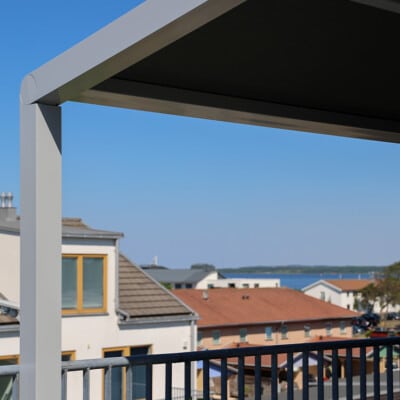 Pergolamarkis i närbild med utsikt över hustak och hav i bakgrunden.